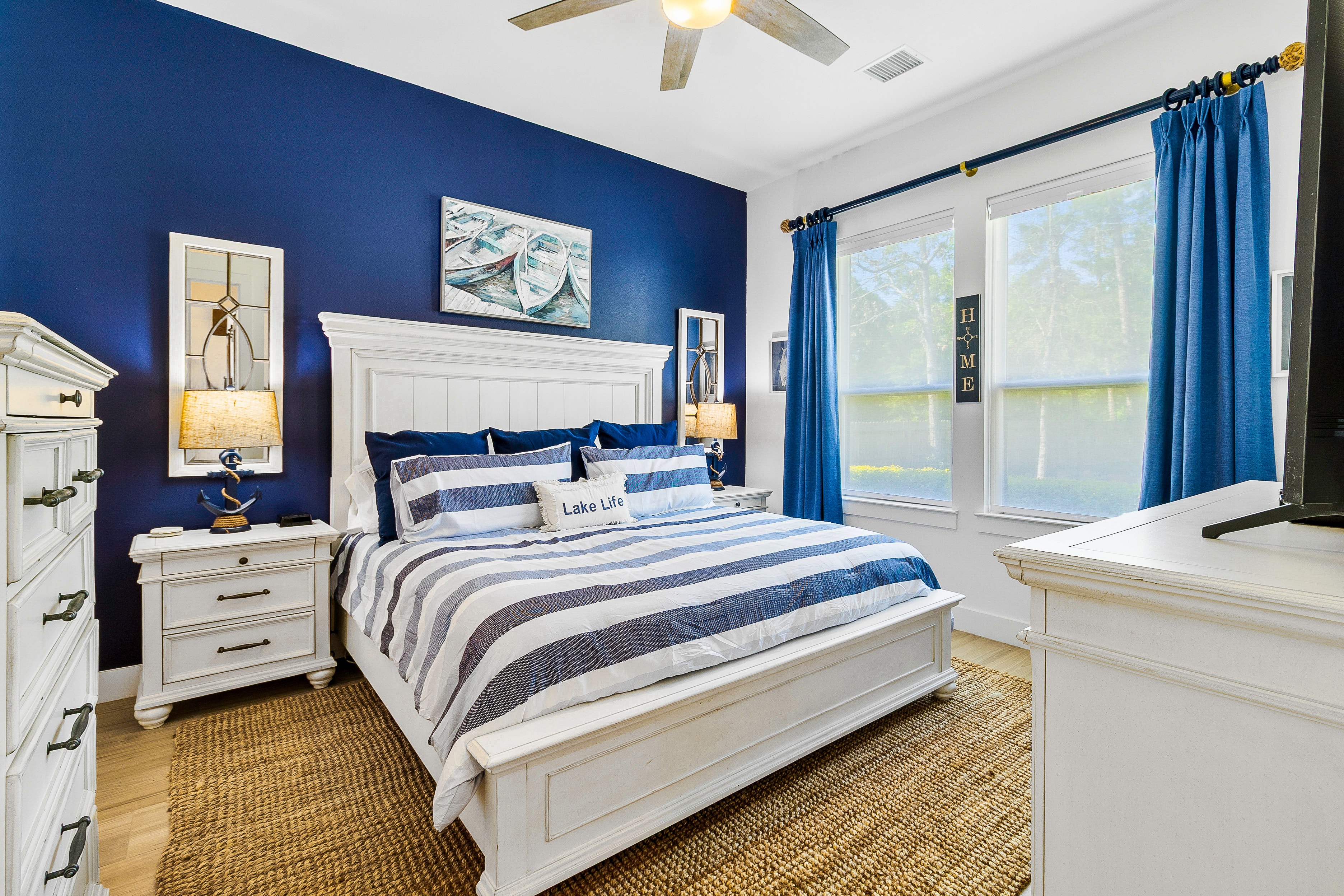 Master bedroom with navy blue accent wall and striped bedding